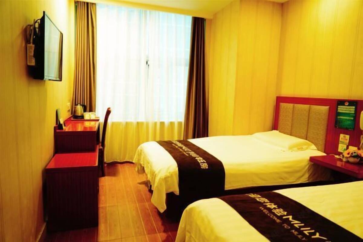 A hotel room with two beds, a desk, and a chair.