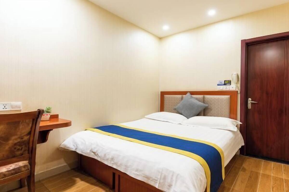 A small, neatly arranged bedroom with a bed, bedside table, and a chair.