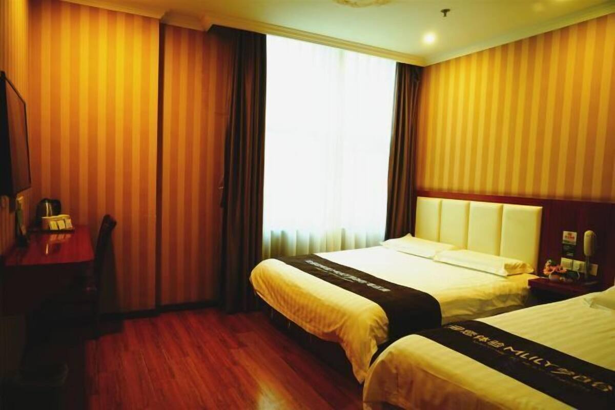 A hotel room with two beds, a desk, and a chair.