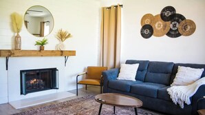 A living room with a fireplace, a sofa, a coffee table, and decorative wall art.