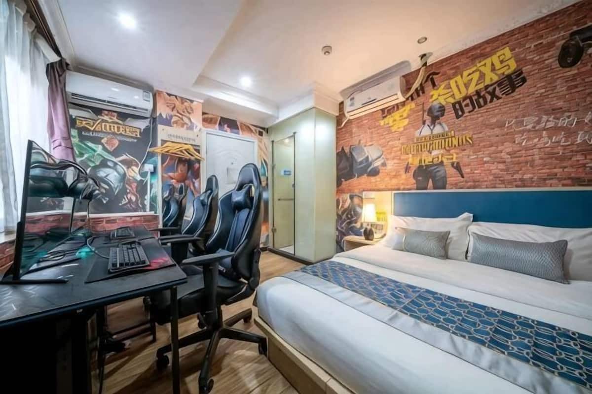 A bedroom with a bed, desk, chairs, and a wall with a mural.