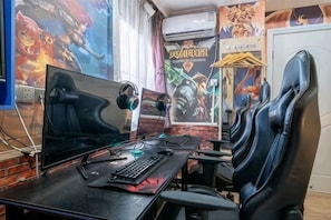 A gaming setup with a monitor, keyboard, headphones, and gaming chairs.