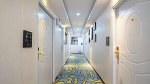 A hotel hallway with a patterned carpet, white doors, and a sign indicating room number 8410. - 8 Inn (Shenzhen)