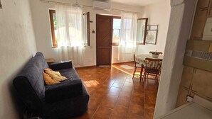 Un salon avec un canapé, une table à manger et des chaises, et une porte qui donne sur une autre pièce.