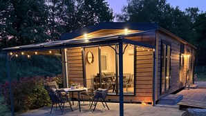 A covered outdoor seating area with tables and chairs, a pergola, and string lights. - Tiny-haus Park - Auszeit am Alfsee (Rieste)