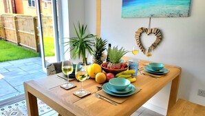 A dining table with a fruit bowl, wine glasses, and a heart-shaped decoration on the wall. - Seaside beach themed home with garden and driveway (Lytham St Annes)