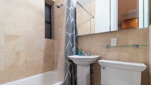 A bathroom with a bathtub, a sink, and a toilet. - Lovely 2 bedroom Central Manhattan (New York)