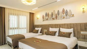 A hotel room with two beds, a chandelier, a wall art piece, and a bedside table. - safa hotel old city (Istanbul)