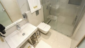 A modern bathroom with a glass-enclosed shower, a white sink, and a toilet. - safa hotel old city (Istanbul)