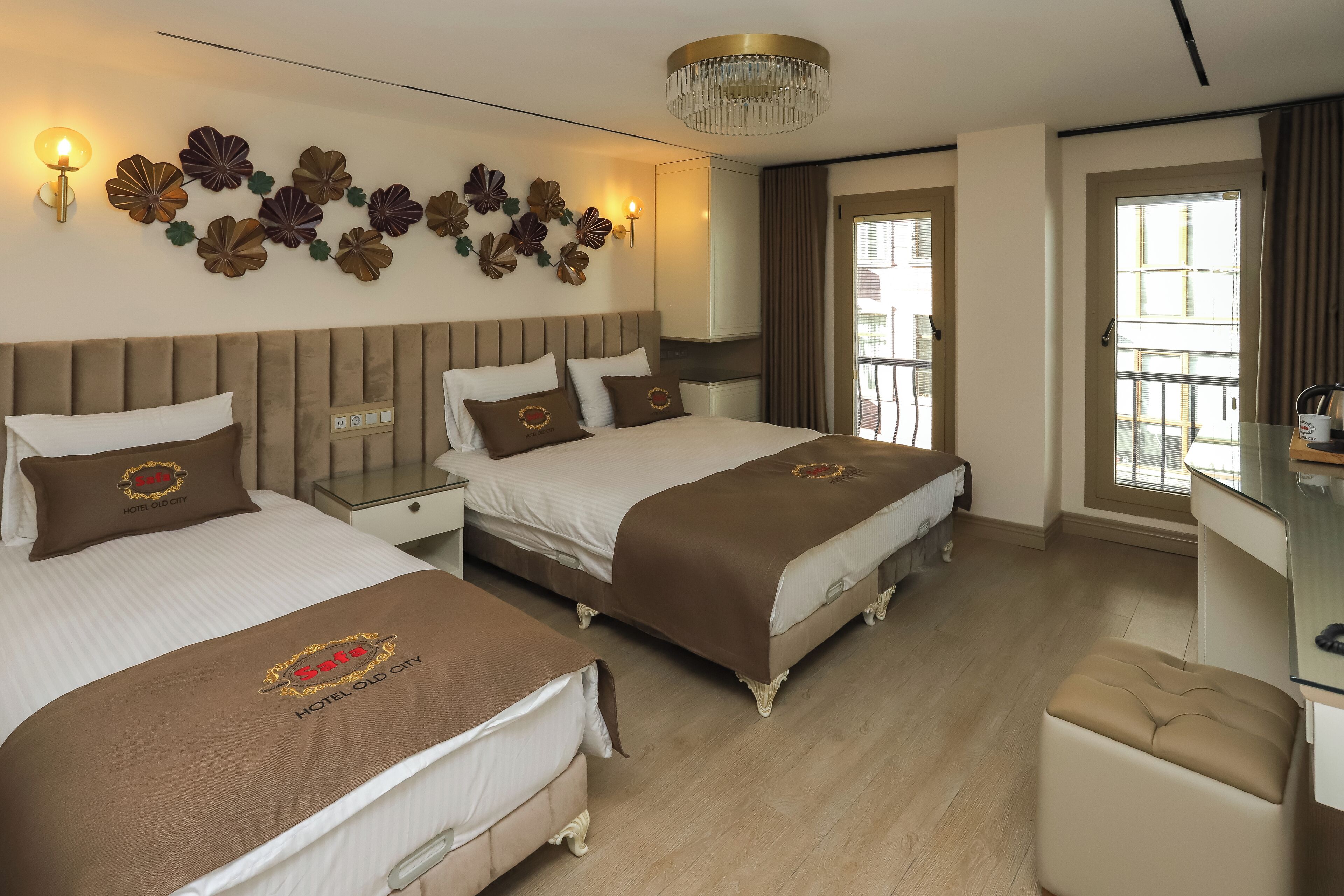 Habitación de hotel con tres camas, una araña y una vista al exterior.