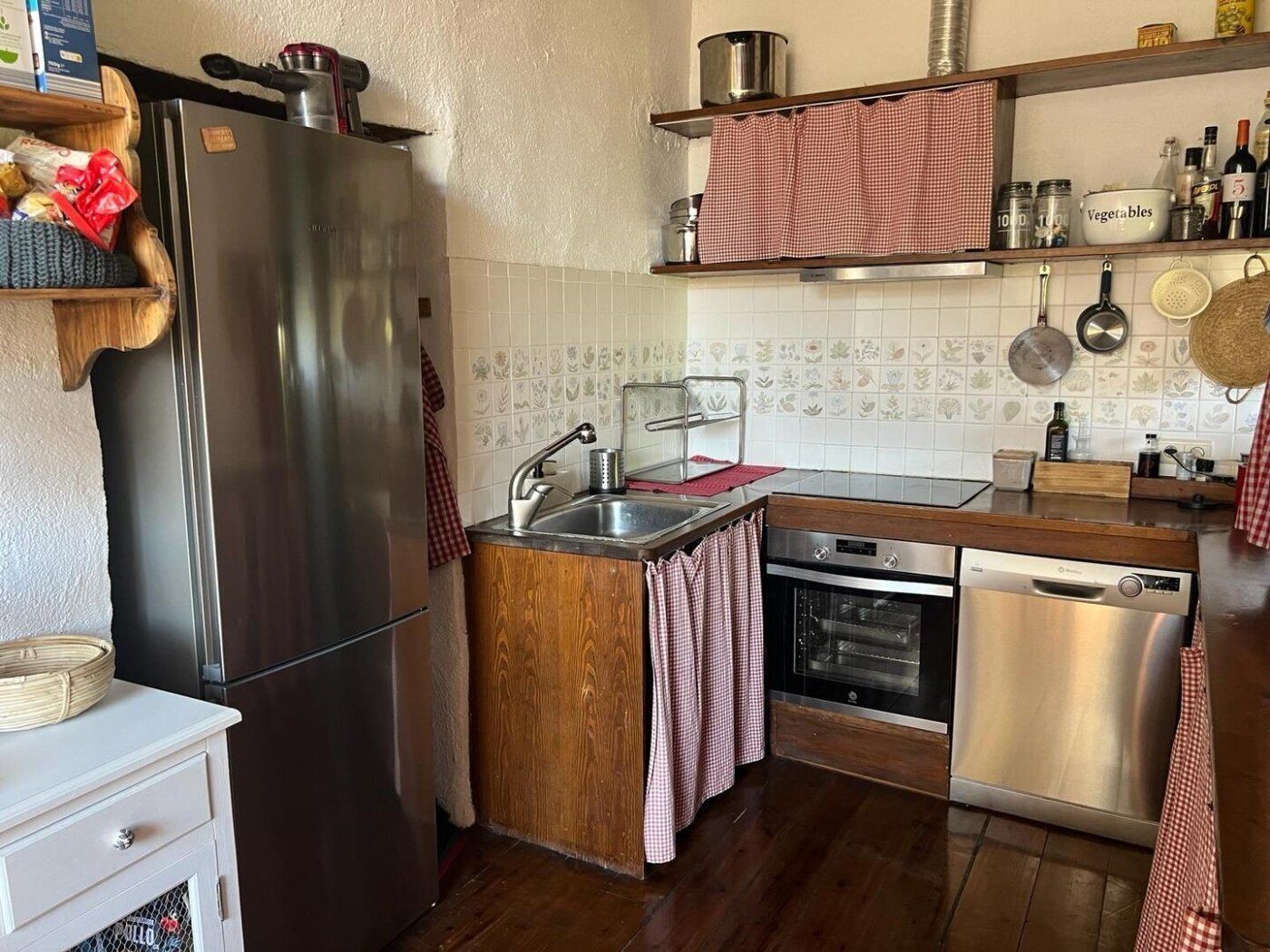 A kitchen with a stainless steel refrigerator, a wooden countertop, a sink, a stove, and a dishwasher.