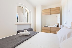 Ein modernes Hotelzimmer mit Bett, Sitzbank, Kleiderschrank und einem Fenster mit Blick.