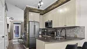 Una cocina moderna con armarios blancos, electrodomésticos de acero inoxidable y encimera de granito.