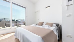A modern bedroom with a large bed, a sliding glass door to a balcony, and a white wall with a phone and light switch. - Casa da Suite Mirabello (Milan)