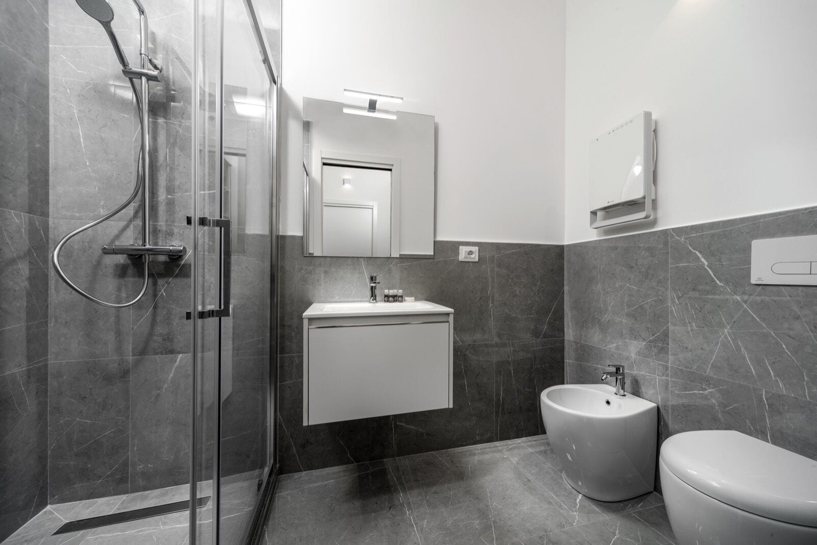 A modern bathroom with a glass-enclosed shower, a white sink, and a toilet.