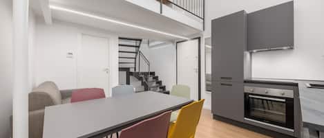 A modern kitchen with a dining area, a staircase, and a built-in oven.