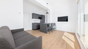 A modern living space with a grey sofa, a kitchen area with a microwave, and a dining table with chairs. - Casa da Suite Mirabello (Milan)