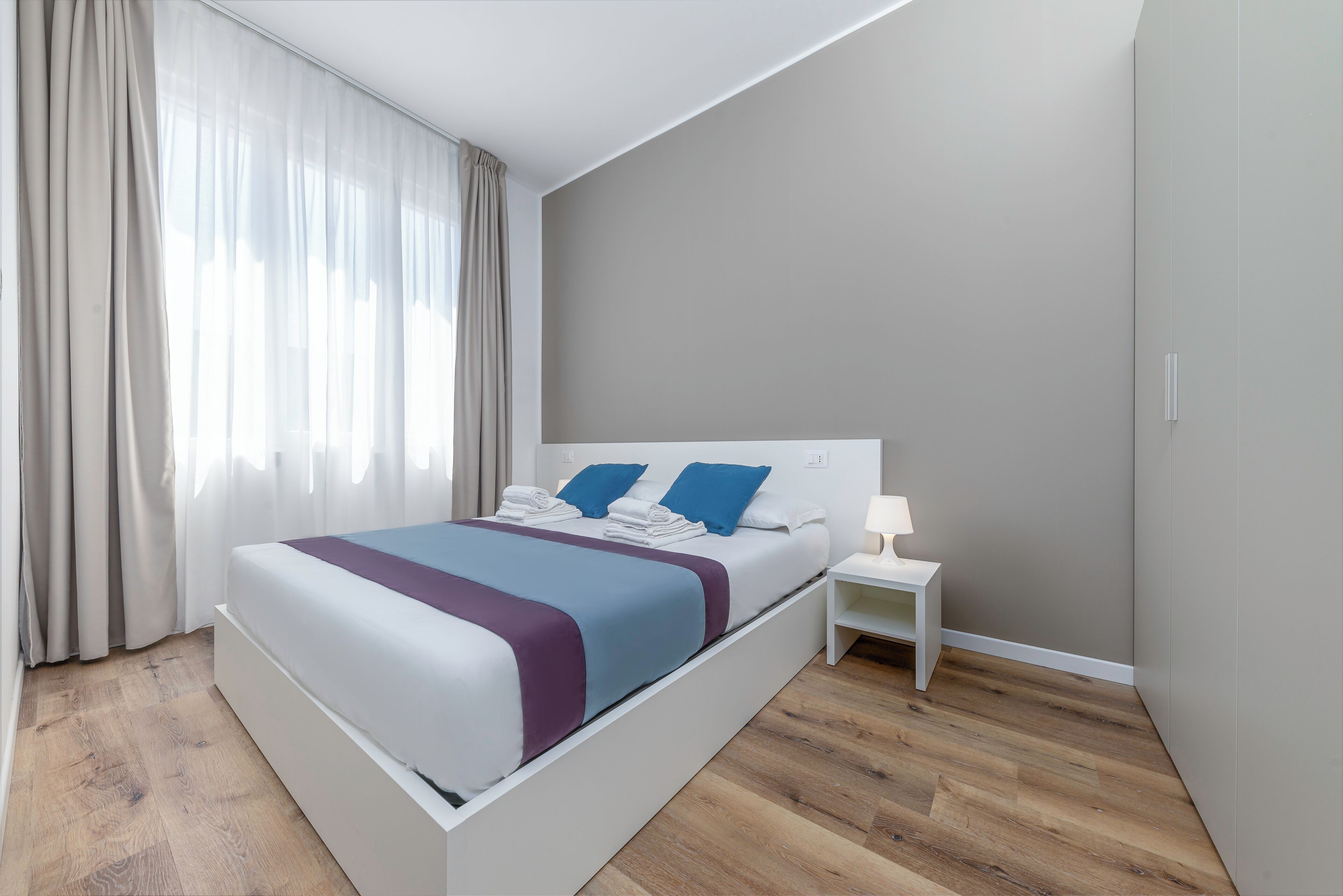 A modern bedroom with a large bed, a bedside table, and a nightstand.