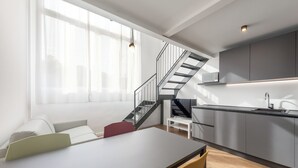 A modern kitchen with a built-in stove, a dining area with a table and chairs, and a staircase leading to an upper level. - Casa da Suite Mirabello (Milan)