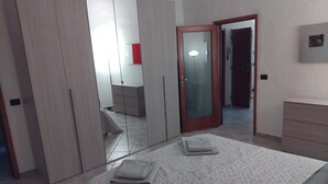 Une chambre à coucher comprenant un lit, une armoire, une commode et une porte donnant sur une autre pièce.