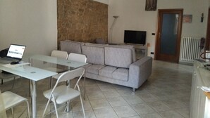 Un salon avec un canapé, une table en verre et un téléviseur.