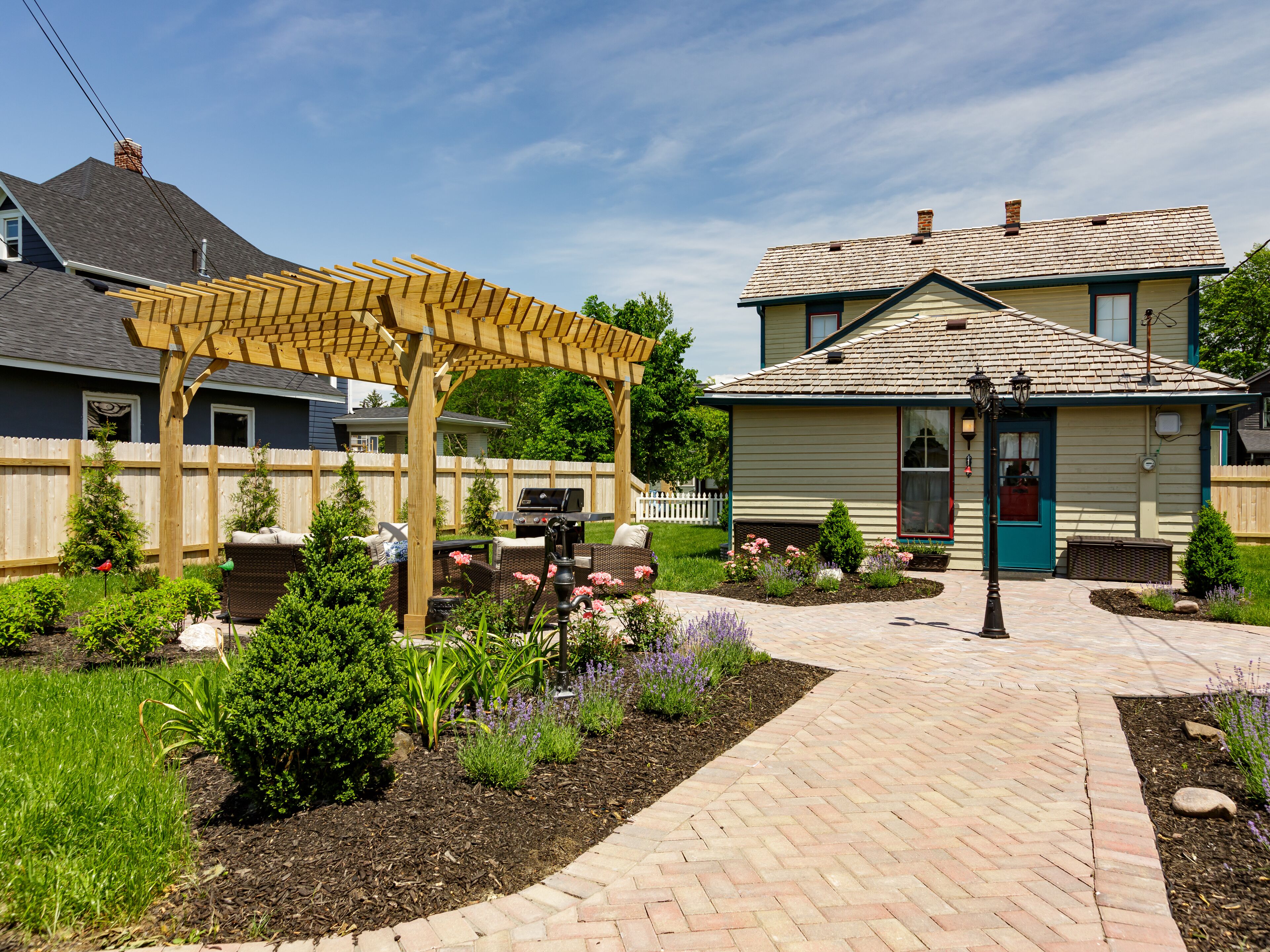 Ein Wohnhaus mit überdachter Terrasse, einem gepflegten Garten und einer Fassade mit markantem Eingangsbereich und Fenstern.