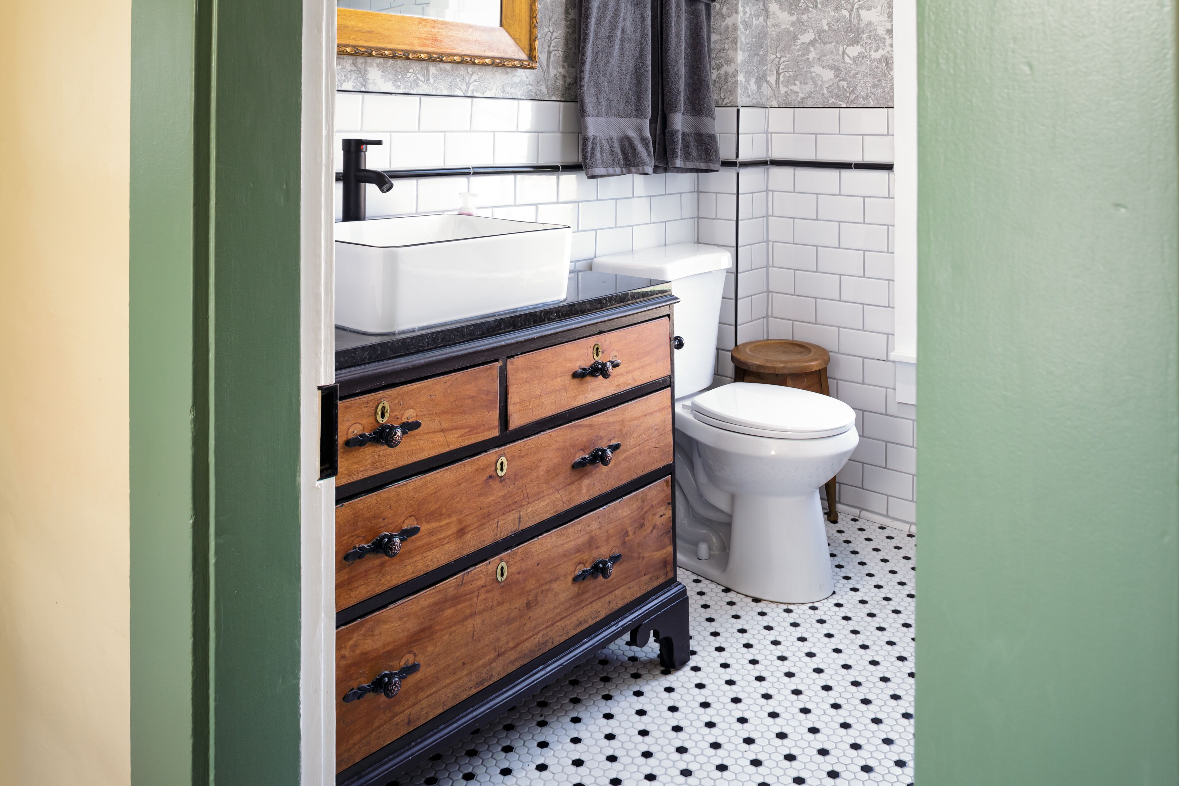 A bathroom with a wooden vanity, a white toilet, and a tiled floor.
