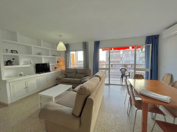 A modern living room with a sofa, TV, and dining area.