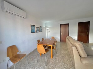 A room with a wooden dining table, six chairs, a beige sofa, and a door.