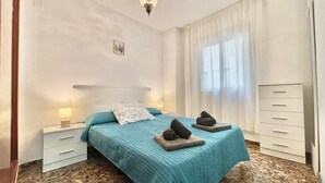 A bedroom with a bed, two bedside tables, a nightstand, a dresser, and a window with curtains. - TERRASOL FAROMAR 4 (Torre del Mar)