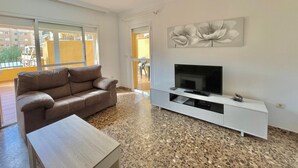 A living room with a sofa, TV, and artwork on the wall. - TERRASOL FAROMAR 4 (Torre del Mar)