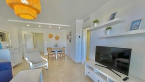 A modern living room with a TV, white furniture, and a dining area. - TERRASOL AZUCARERA 4 (Torre del Mar)