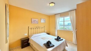 Un dormitorio con una cama, una mesita de noche, una ventana con cortinas y dos obras de arte colgadas en la pared.
