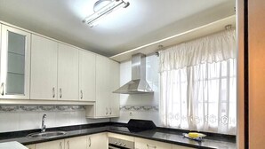 Una cocina con armarios, un fregadero, una estufa y una ventana con cortinas.