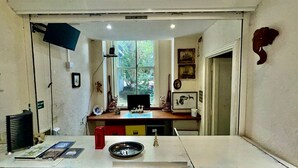 A kitchen with a window, a sink, a countertop with a bowl, and various kitchen items. - Cumberland Hotel (Workington)