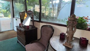 A room with a large window, a chair, a small table with a statue, and a dresser. - Cumberland Hotel (Workington)