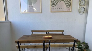 Een kamer met een houten tafel, bankjes, een potplant en kunstwerken in een lijst aan de muur.