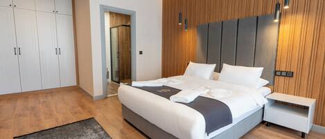 A modern bedroom with a large bed, wooden panel wall, and built-in wardrobe.