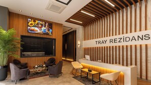 A reception area with a modern design, featuring a reception desk, seating area, and a large TV screen. - TRAY TRABZON  (Yomra)