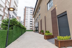 Un edificio moderno de apartamentos urbanos con un diseño limpio y minimalista, que cuenta con un patio central con plantas en macetas y un seto bien cuidado.