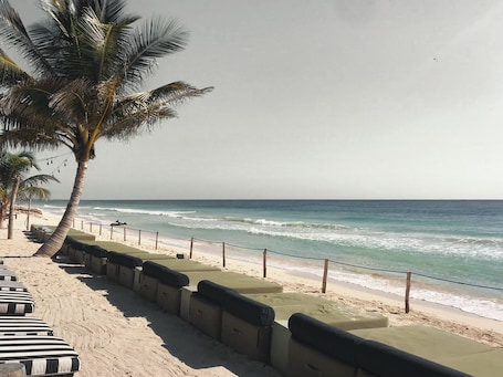 Playa privada, arena blanca, sillas reclinables de playa, sombrillas