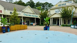 A beachfront property with a covered walkway, a beach shop, and a Vacasa branded building. - ServingSand West @ SeaColony: Carriage House between Tennis and Fitness Center! (Bethany Beach)