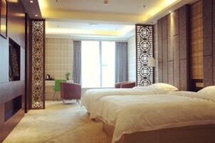 A hotel room with two beds, a desk, a chair, a TV, and a large window with curtains.