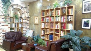 Una biblioteca con estanterías, sillones de cuero y una pared de ladrillo.