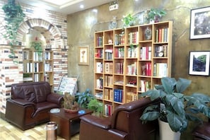 Eine Bibliothek mit Bücherregalen, Ledersesseln und einer Backsteinwand.