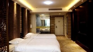 Habitación de hotel con cama, escritorio y baño visible a través de una puerta de vidrio.