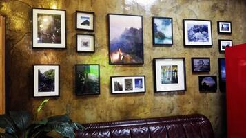 A wall with multiple framed photographs, a brown leather couch, and a red object on the right.