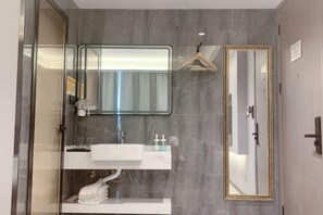 Une salle de bain moderne avec une douche à l’italienne en verre, un meuble-lavabo blanc avec un miroir et un grand miroir mural.