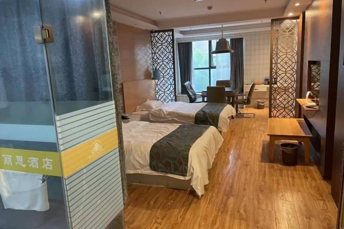 Een hotelkamer met twee bedden, een bureau, een stoel, een klein tafeltje en een raam.