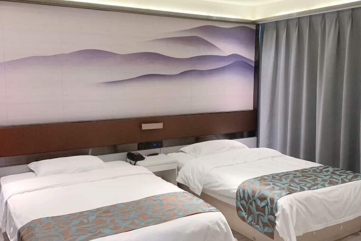 Een hotelkamer met twee bedden, een groot muurschilderij, een nachtkastje met een telefoon en een gordijn.